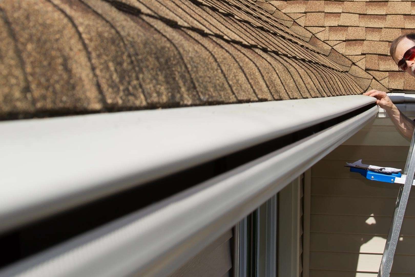 homeowner inspecting seamless rain gutter